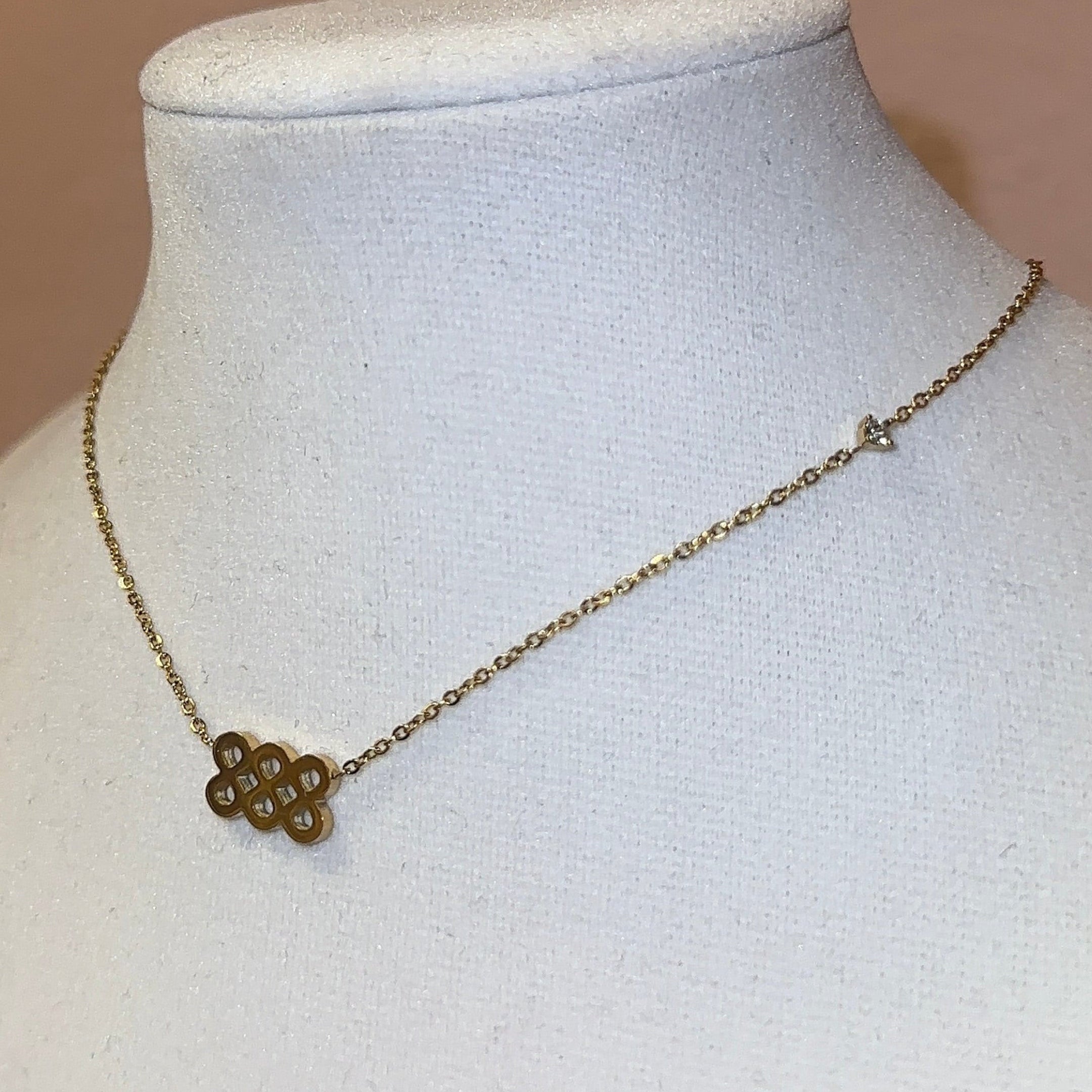 Necklace with a pendant on a mannequin bust against a pink framed picture