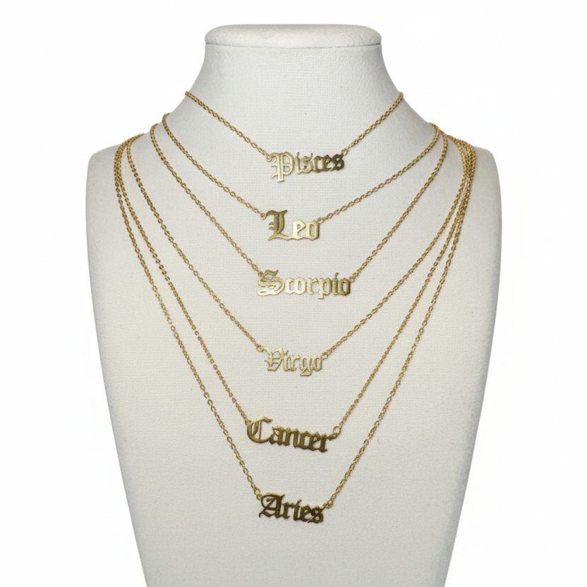 Set of gold necklaces with zodiac symbols on a white bust against a gray background