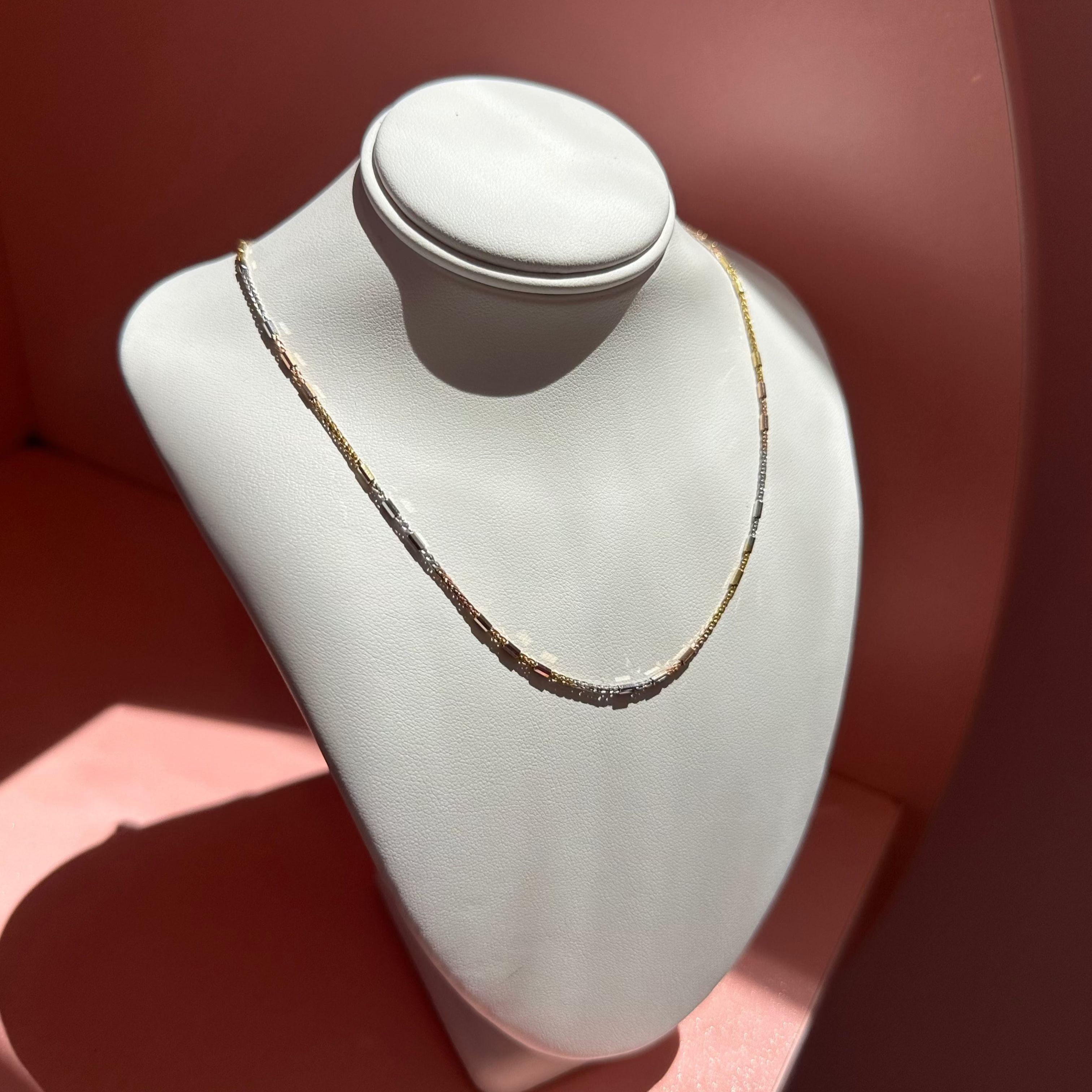 Necklace on a white mannequin bust against a pink background