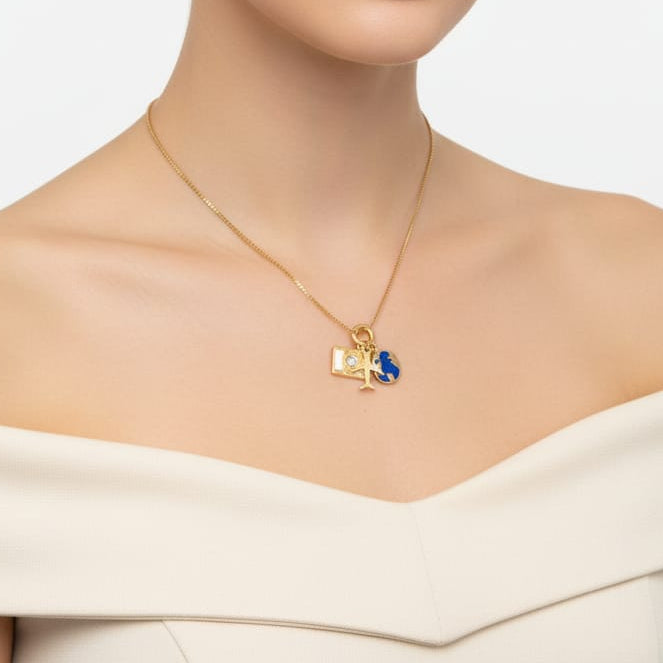 A woman with her hair pulled back wears a delicate gold necklace with a small pendant featuring a blue gemstone, set against a clean white background.
