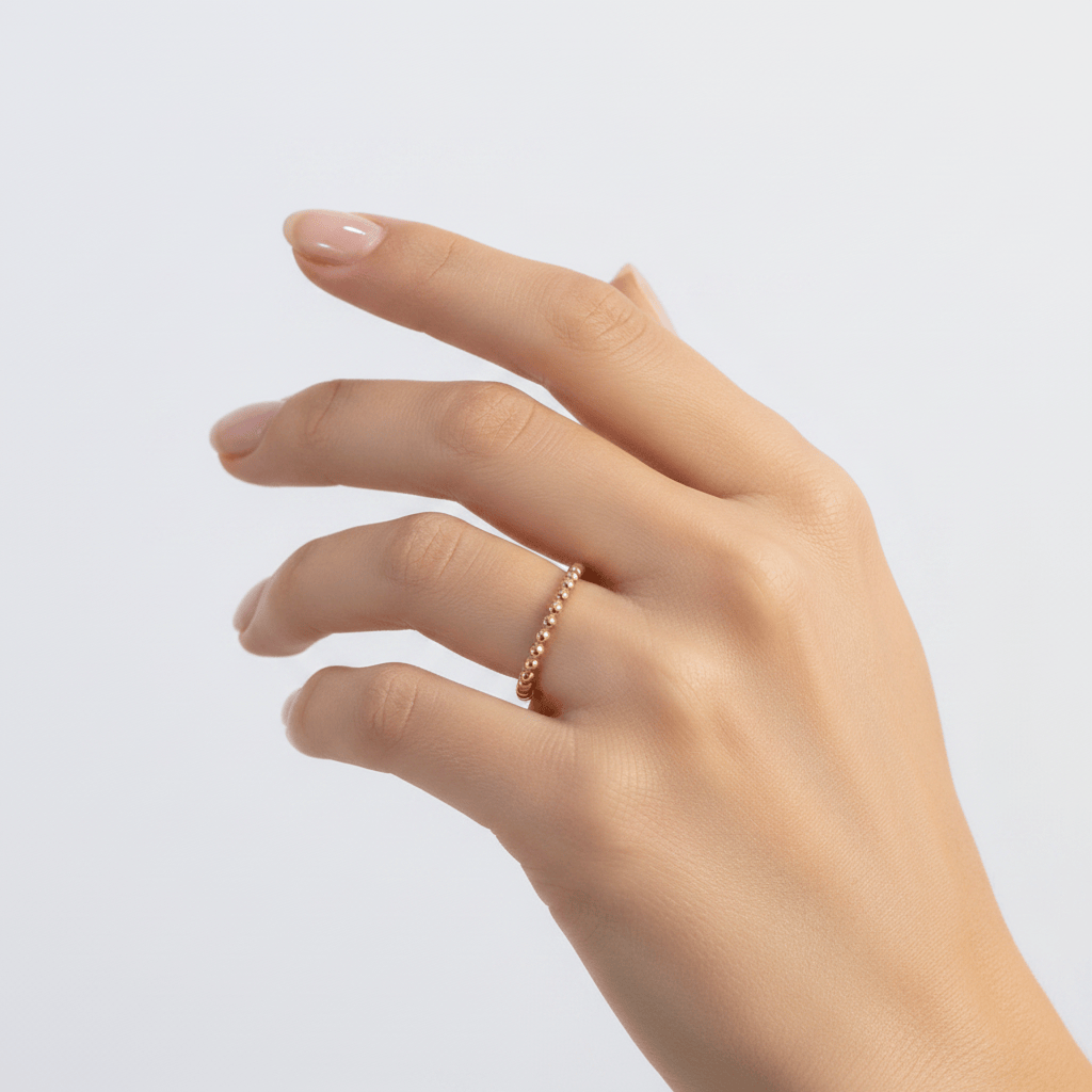 Hand wearing a gold ring on a light gray background