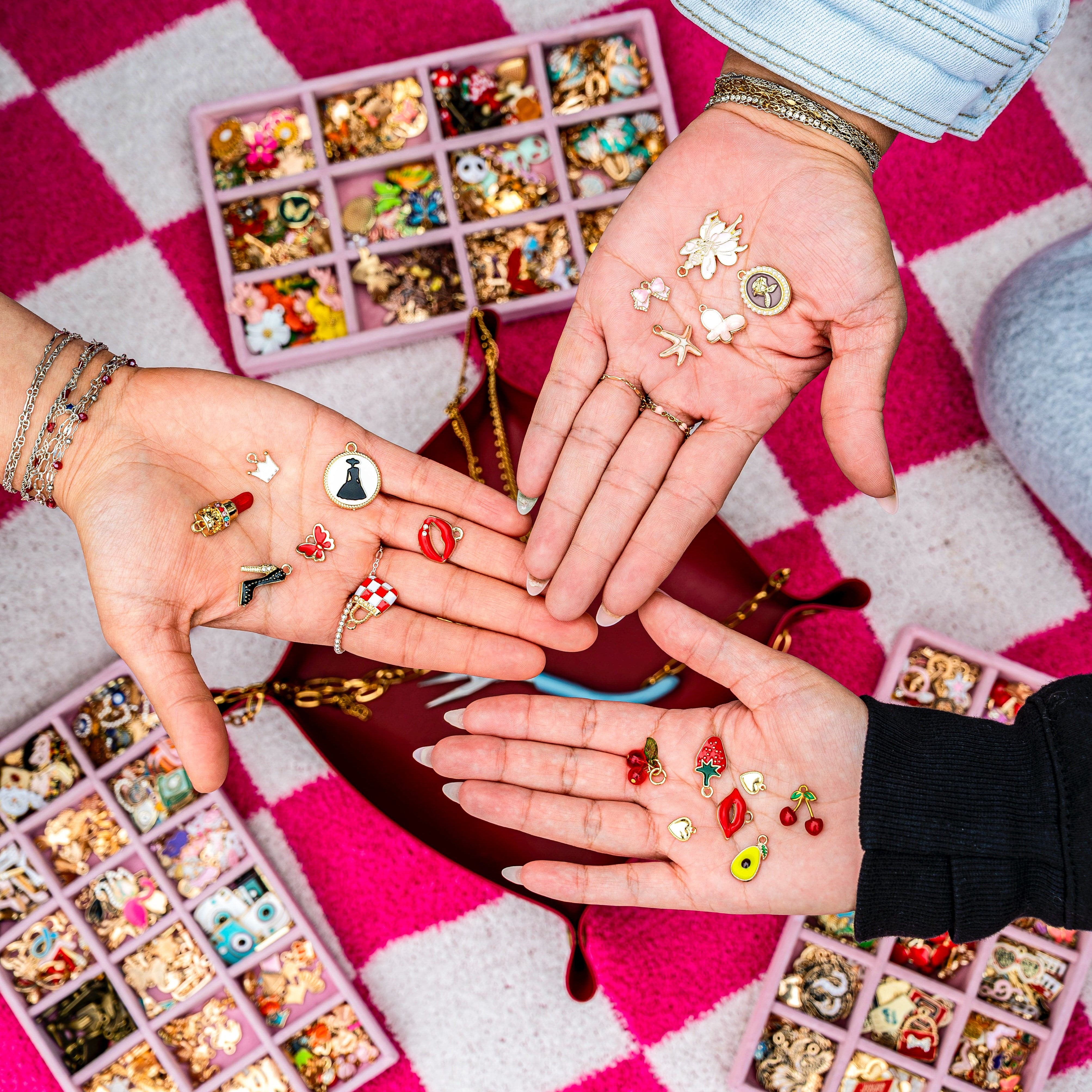 Hands displaying various small decorative items on a checkered fabric background