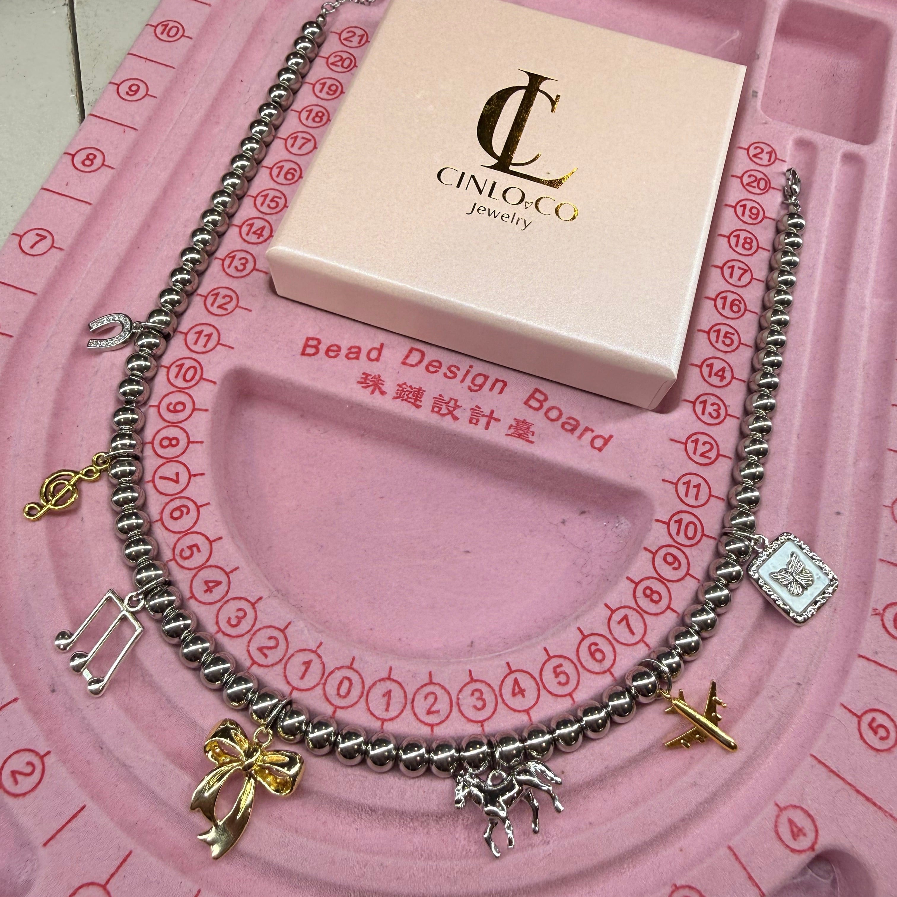 Bracelet with charms on a pink jewelry design board