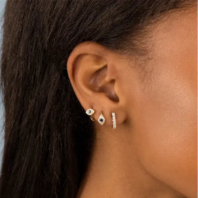 Close-up of an ear wearing multiple earrings against a neutral background