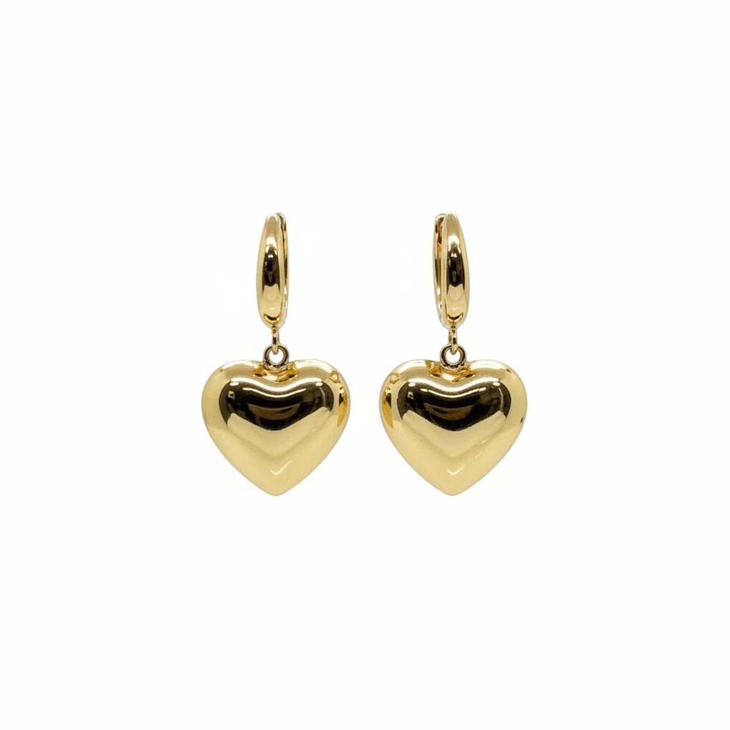 Gold heart-shaped earrings on a pink hexagonal jewelry box with a brand logo, placed in front of decorative elements.