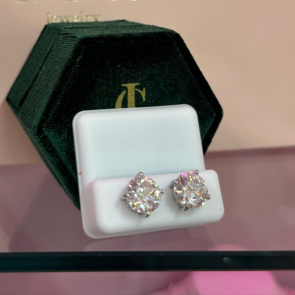 Pair of diamond earrings on a white display card with CinLoco branding in the background.