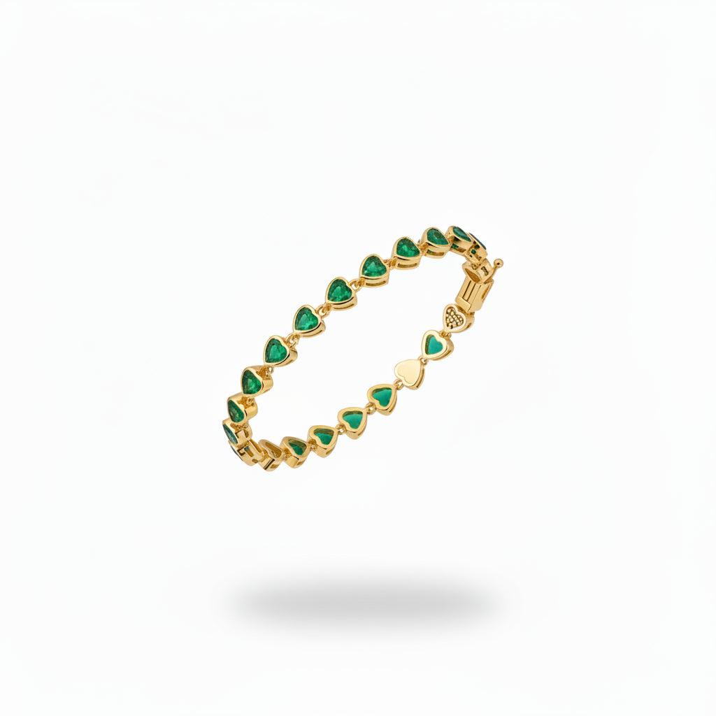 A close-up of a woman's hands and lower face wearing a delicate gold bracelet adorned with small green marquise-cut gemstones, set against a clean white background.