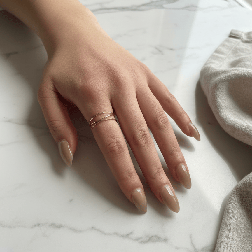 Hand with beige nail polish on a marble surface