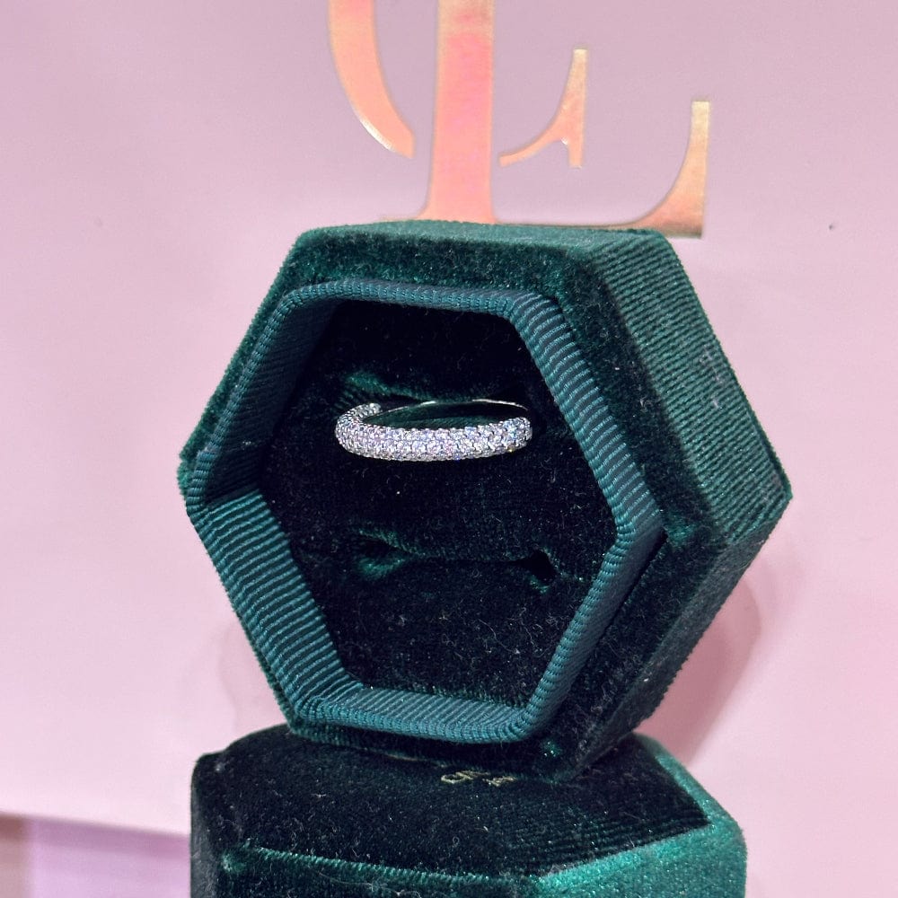 Hexagonal green velvet box with a silver ring on a pink background