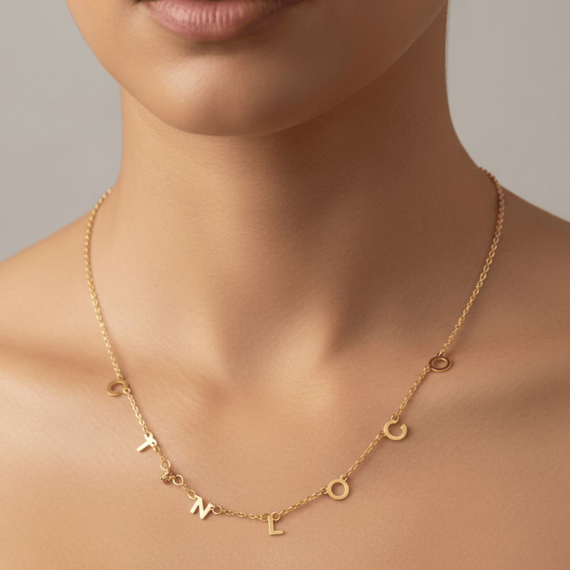 Gold necklace with letter charms on a neutral background