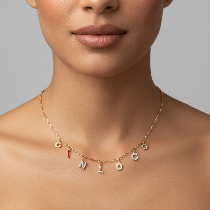Gold necklace with charms on a mannequin bust against a gray background