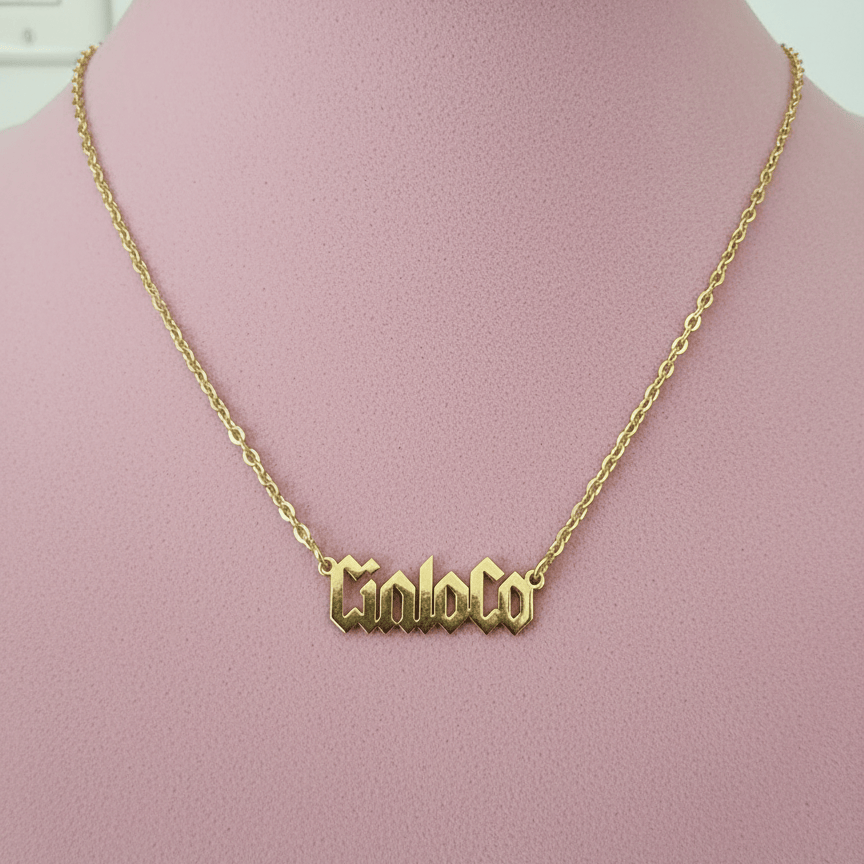 Gold necklace with 'Cinco' pendant on a pink mannequin