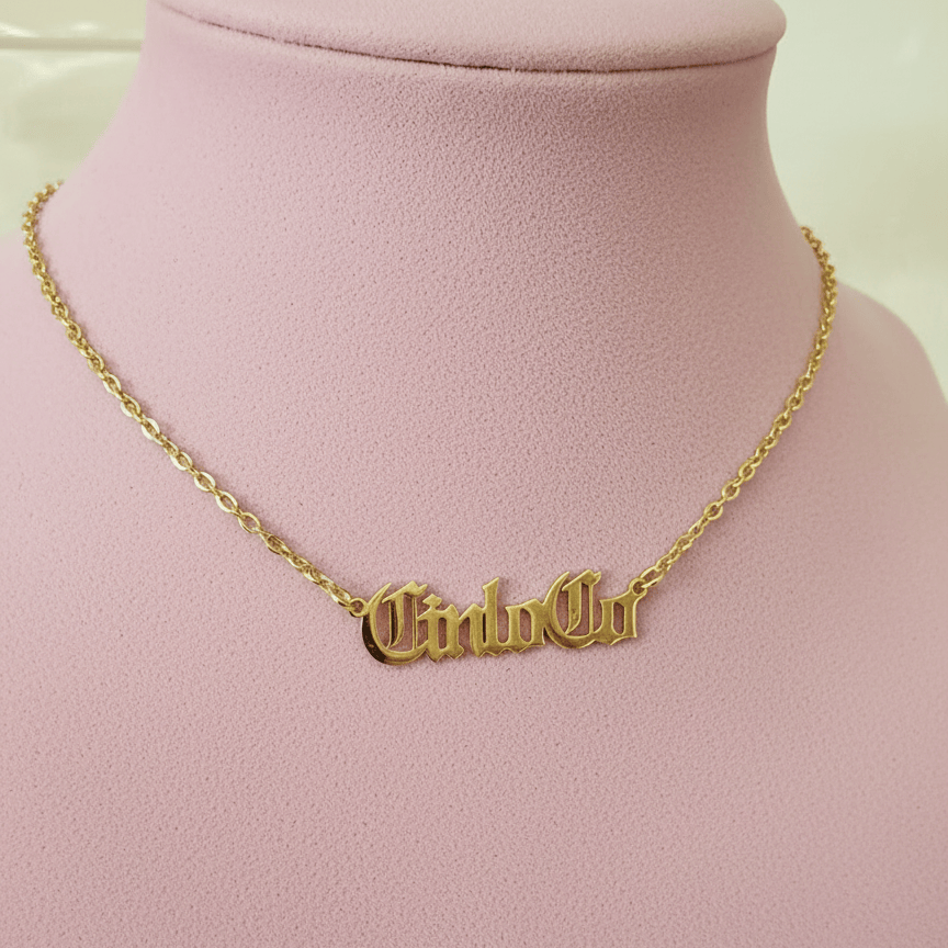 Gold necklace with CUSTOM NAME PLATE pendant on a pink mannequin bust.