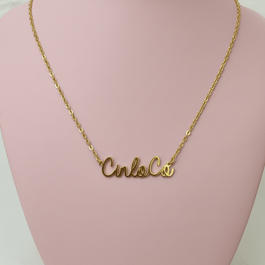 Gold necklace with a customizable name plate pendant on a pink mannequin bust.