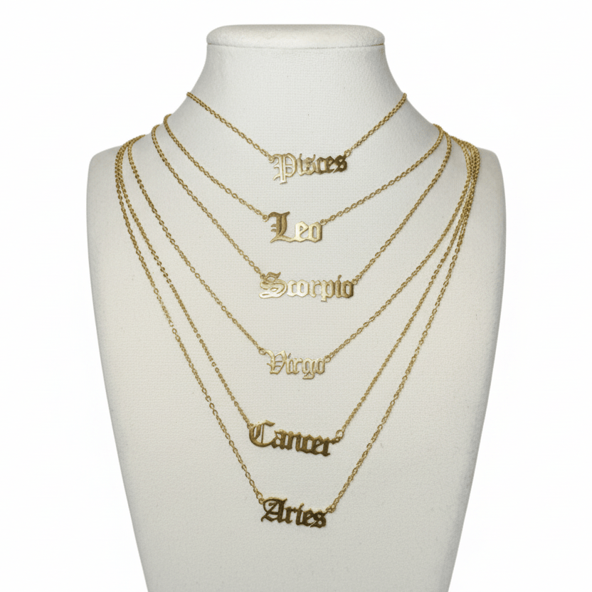 Set of gold necklaces with zodiac symbols on a white bust against a gray background