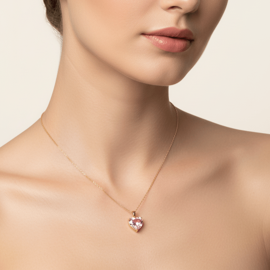 Woman wearing a delicate necklace with a pink heart pendant against a neutral background