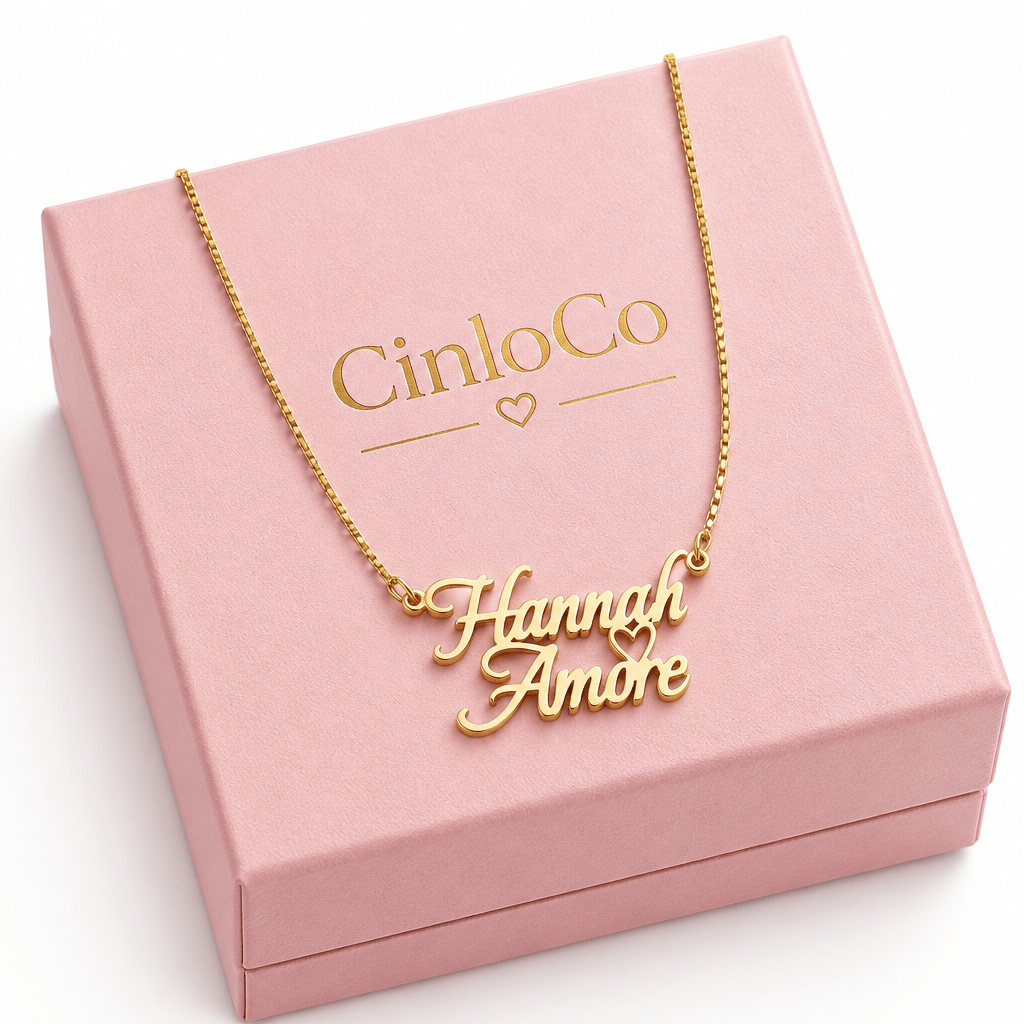 A gold nameplate necklace reading 'Hannah Amore' with a small heart detail, suspended from a gold chain on a plain white background.