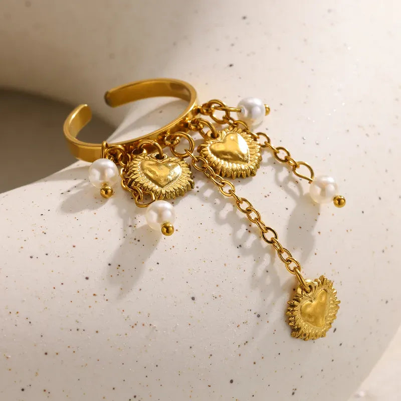 Gold bracelet with heart-shaped charms and pearls on a textured surface