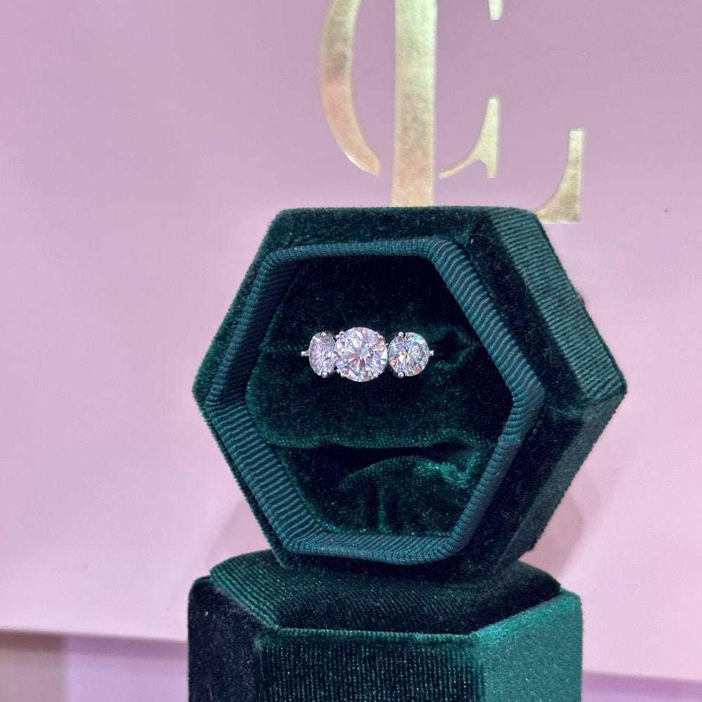 Green hexagonal jewelry box with a pair of diamond earrings on a pink background