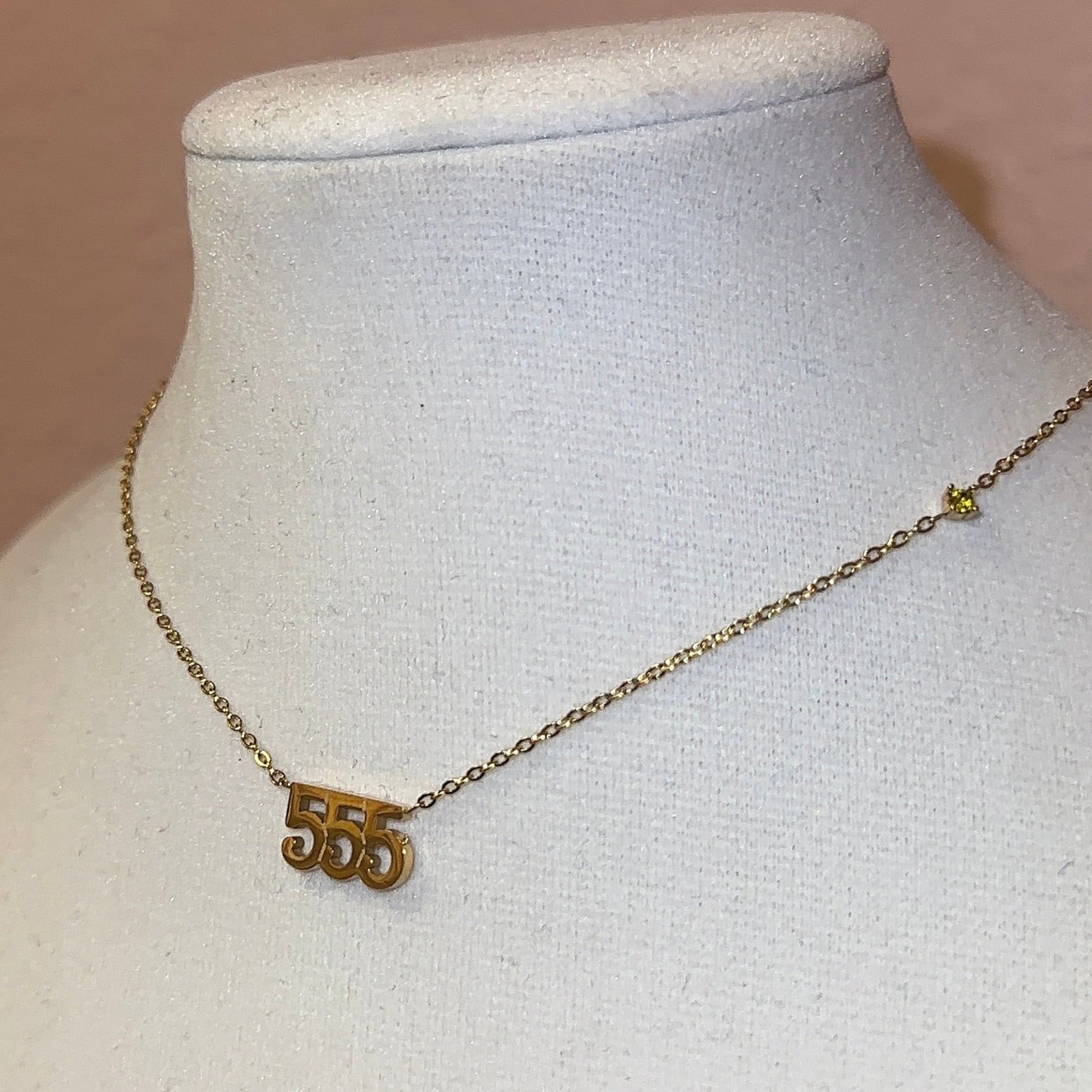 Gold necklace with a pendant on a mannequin bust against a pink frame background