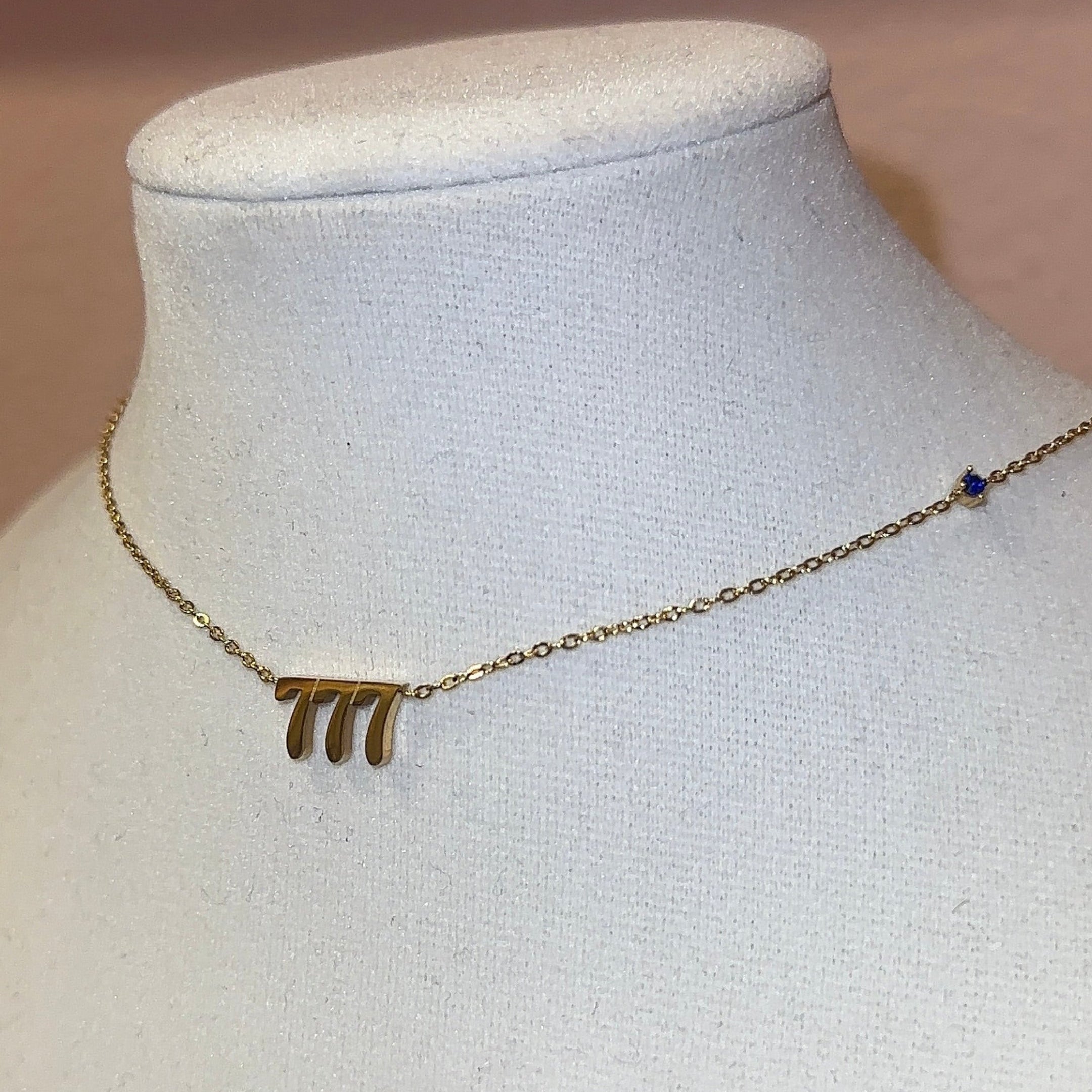 Gold necklace on a mannequin bust with a pink frame in the background