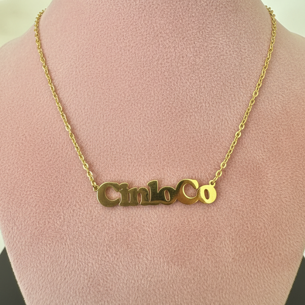 Gold necklace with a customizable name plate pendant on a mannequin bust.