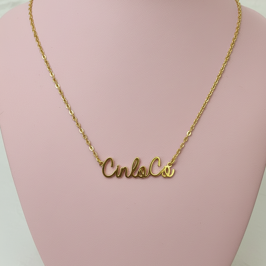 Gold necklace with a customizable name plate pendant on a pink mannequin bust.