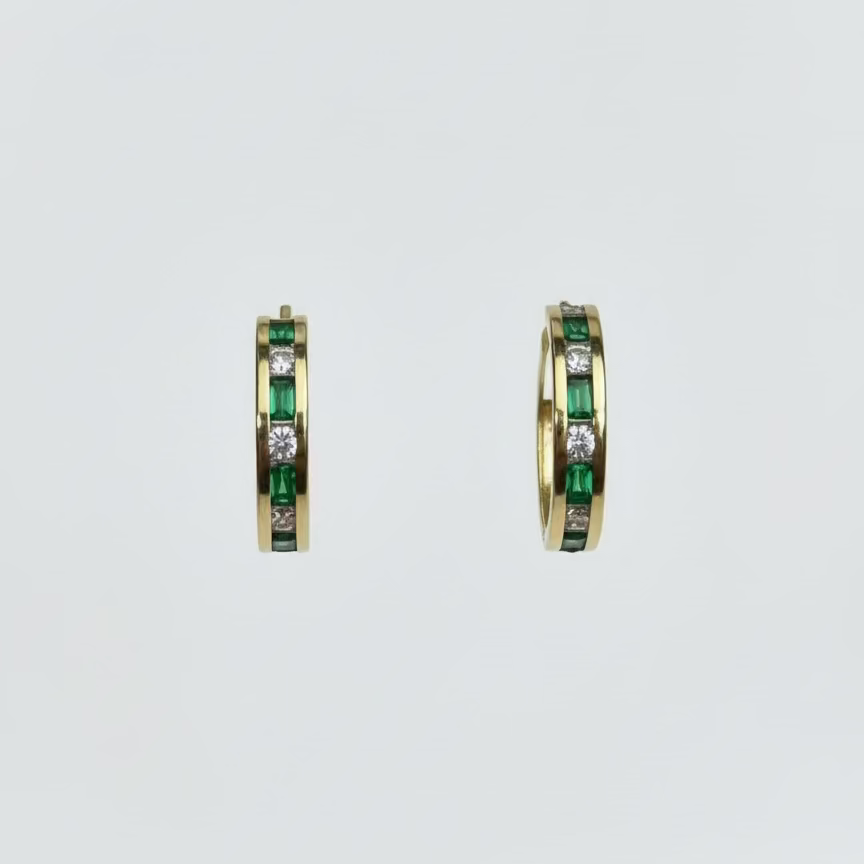 Gold hoop earrings with green gemstones on a light gray background