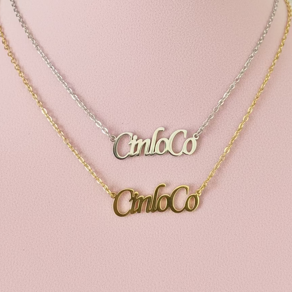 Two gold nameplate necklaces on a pink mannequin bust.