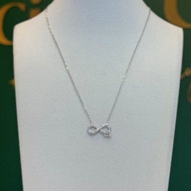 Necklace with a infinity on a mannequin bust against a green background with gold text.