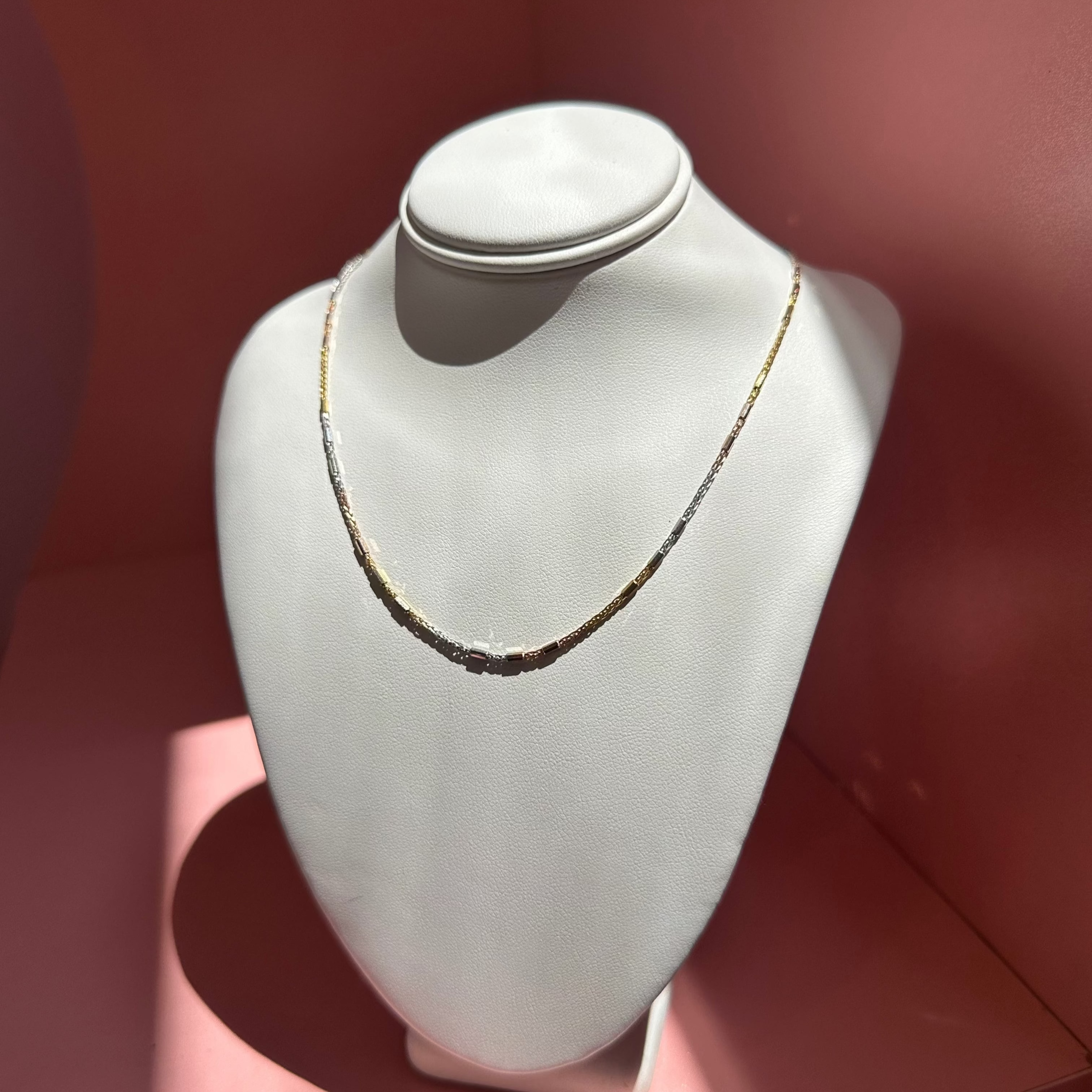 Solid Gold Necklace on a mannequin bust against a pink background