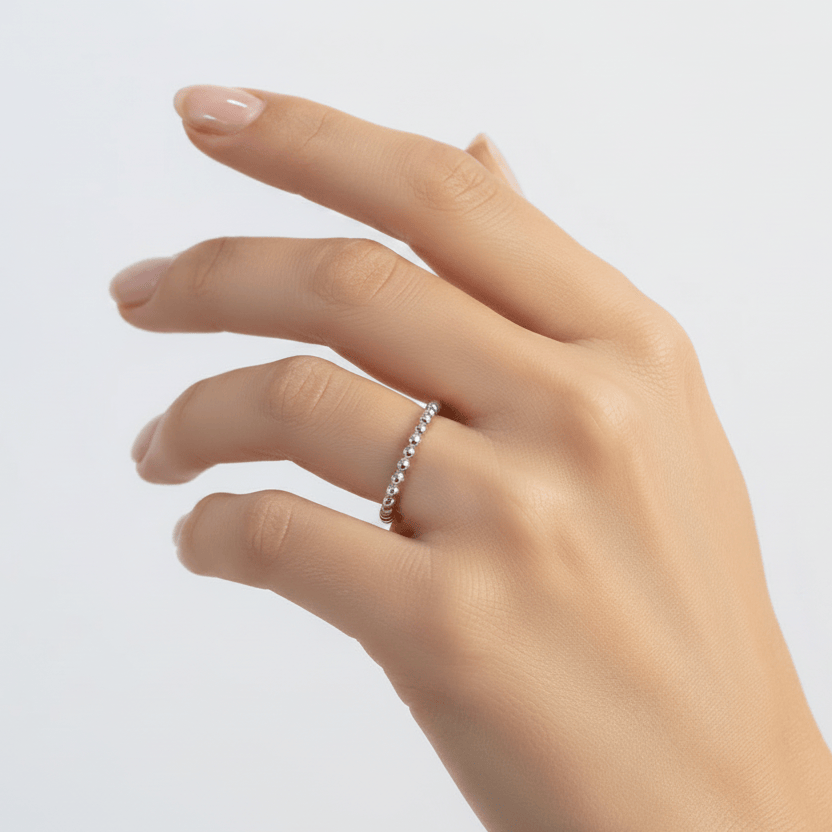 Hand wearing a silver ring on a light gray background