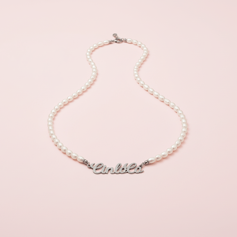 Pearl necklace with a silver nameplate on a pink background