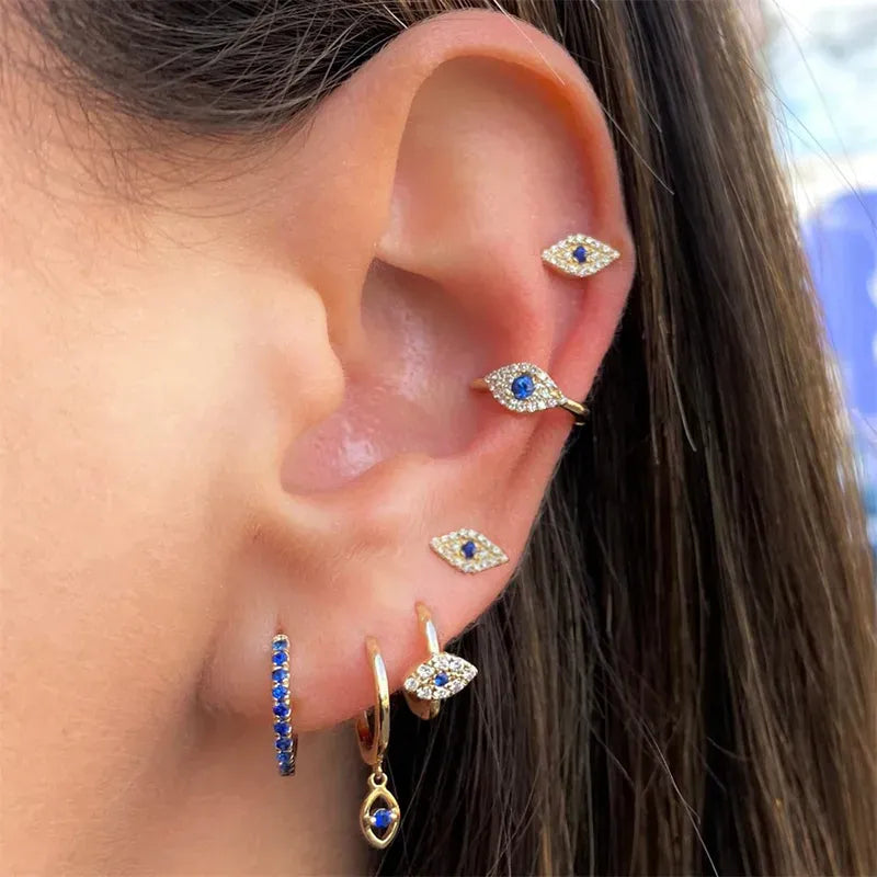 Close-up of an ear wearing multiple gold earrings with blue stones.