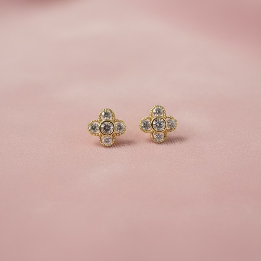 Pair of gold earrings with gemstones on a pink background