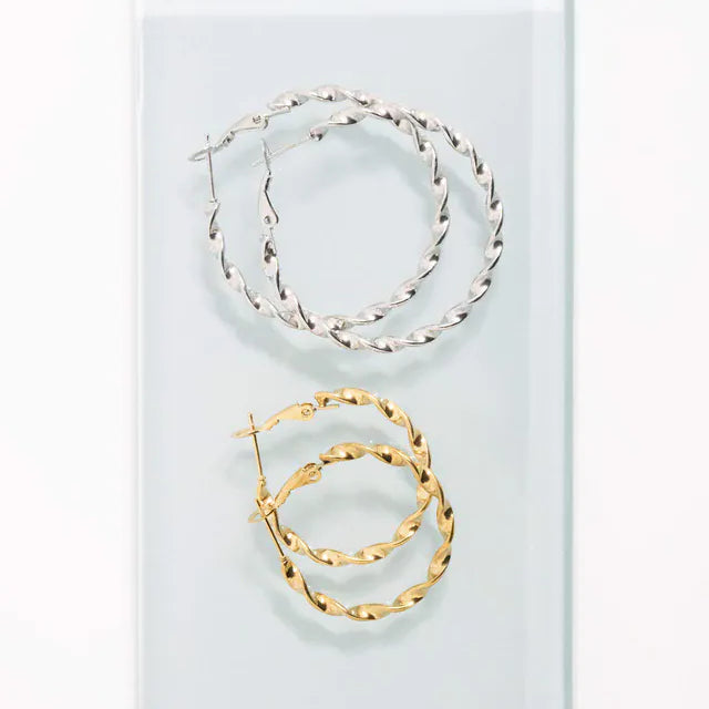 Gold and silver hoop earrings on a light blue background