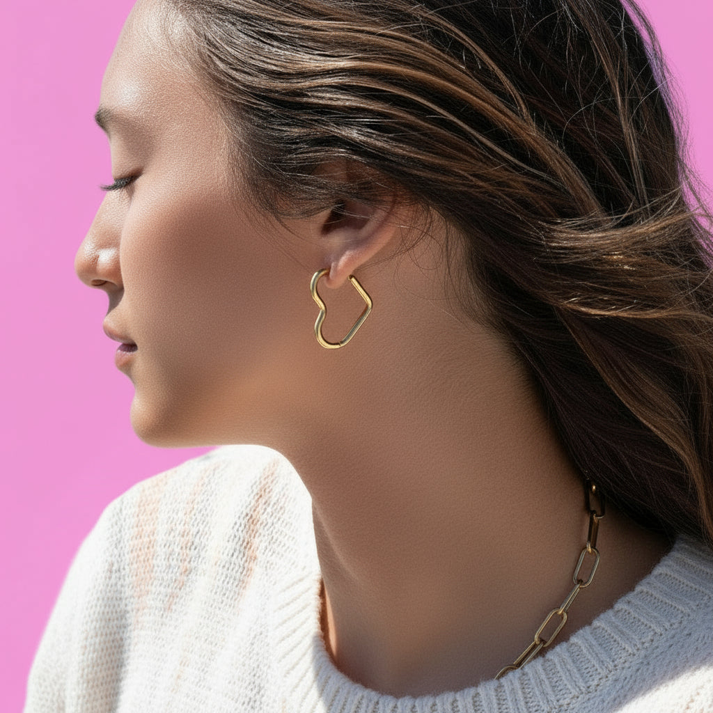 Close-up of a woman wearing a gold heart hoop earring with a blurred background