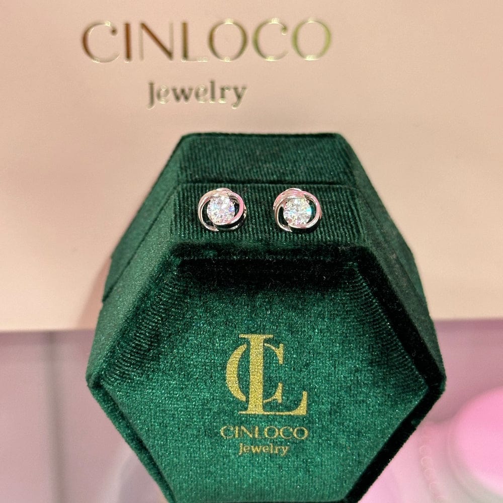 Green jewelry box with Cinloco Jewelry logo containing diamond earrings on a beige background.