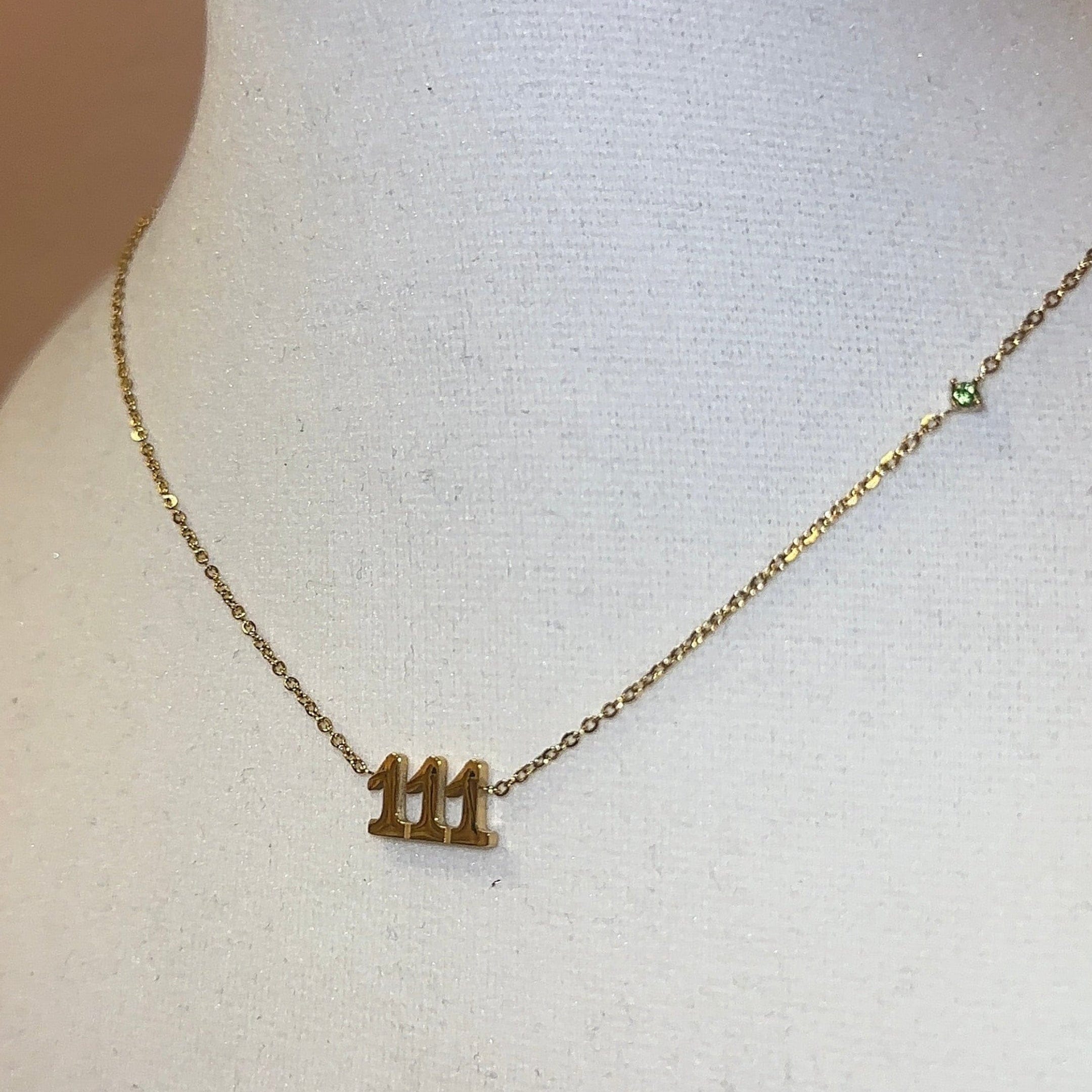Gold necklace with a '111' pendant on a mannequin bust.
