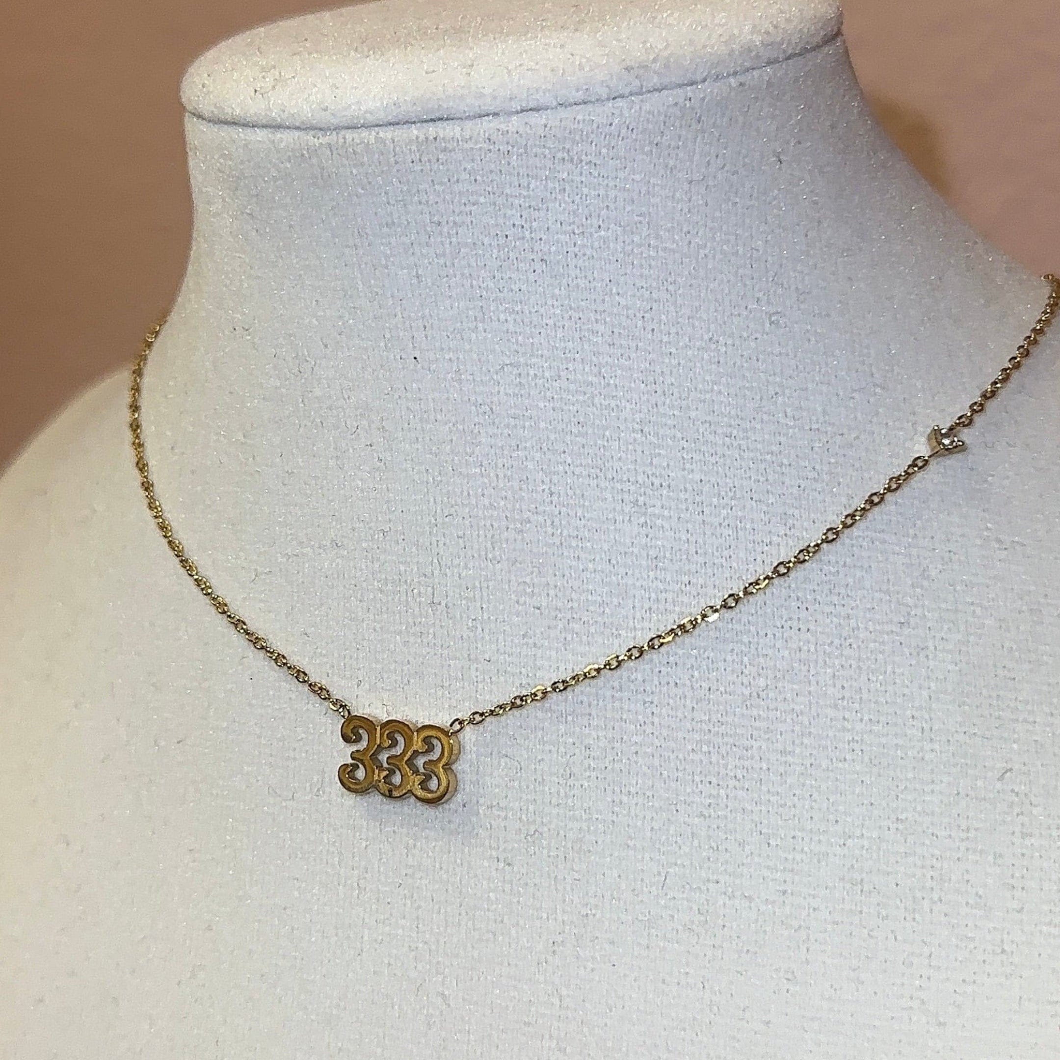 Gold necklace on a mannequin bust against a plain background