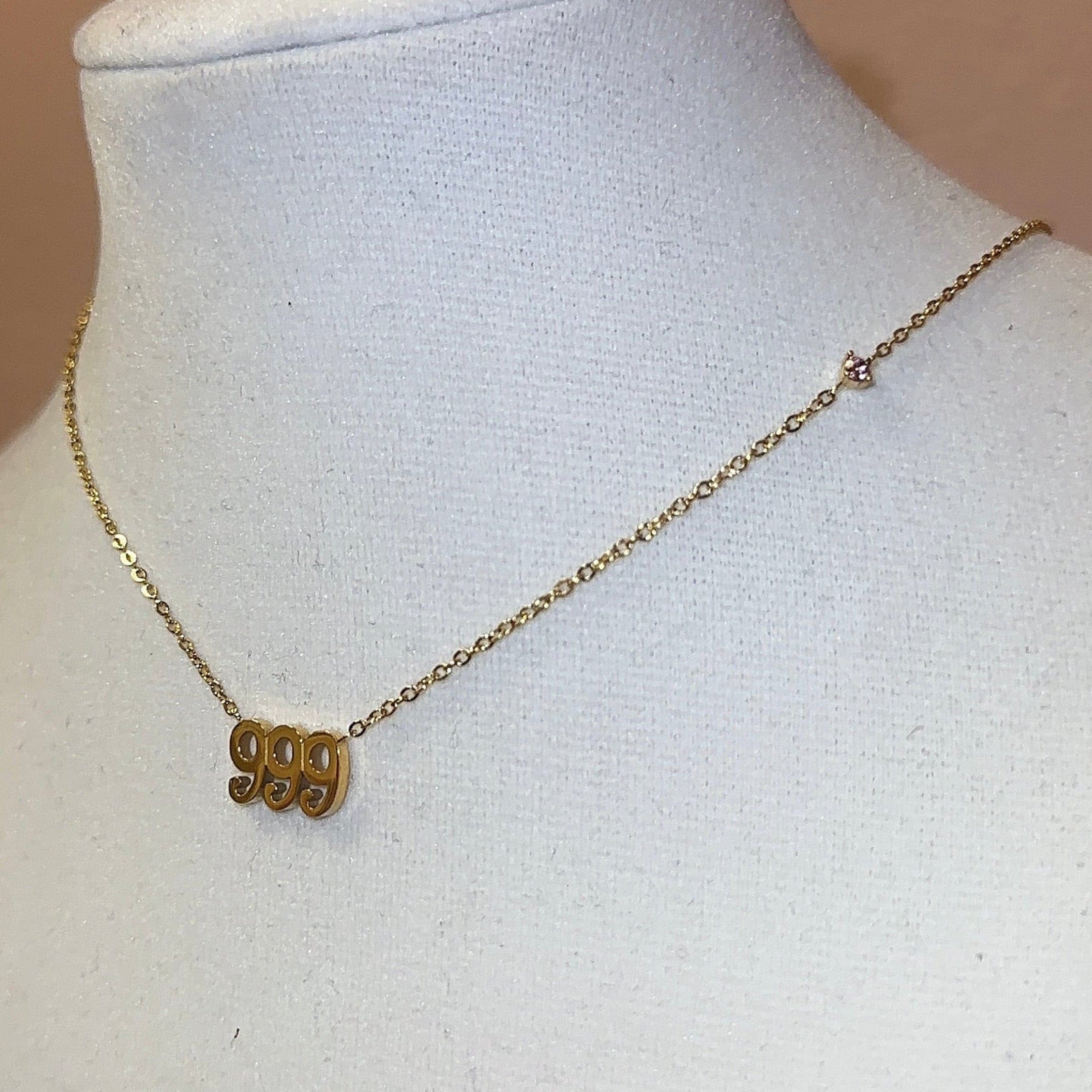 Gold necklace on a mannequin bust with a pink framed picture in the background