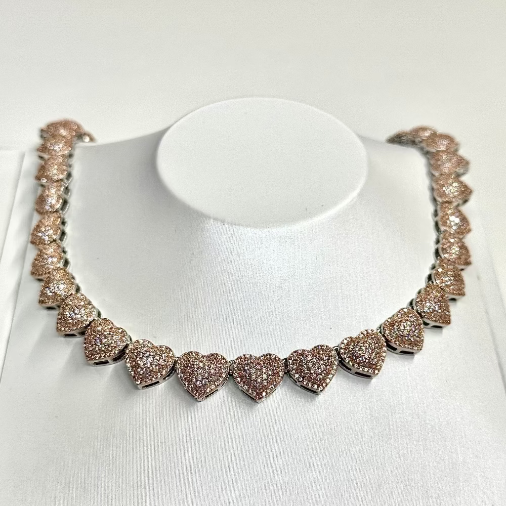Rose gold necklace with heart-shaped diamonds on a white stand