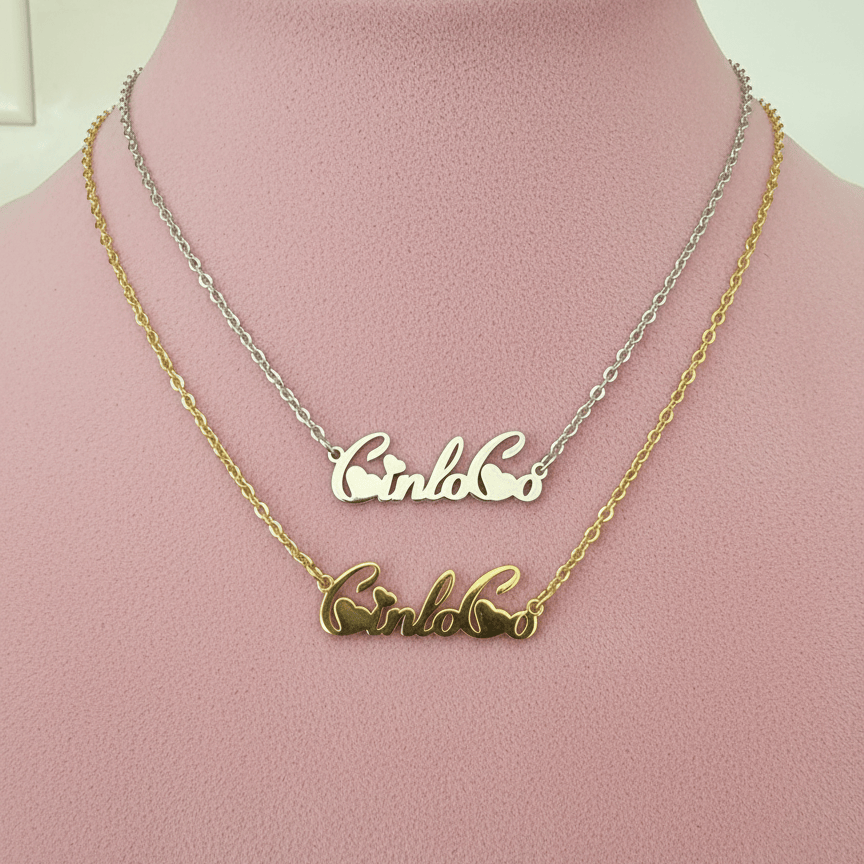 Two nameplate necklaces, one gold and one silver, on a pink mannequin.