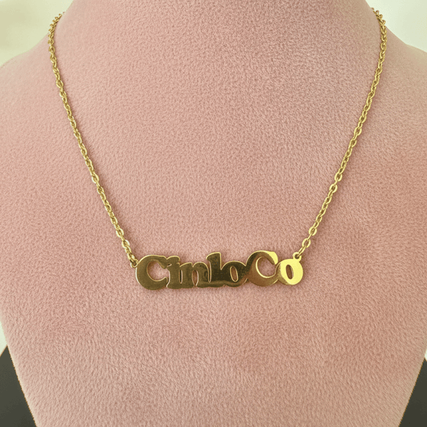 Gold necklace with a customizable name plate pendant on a mannequin bust.