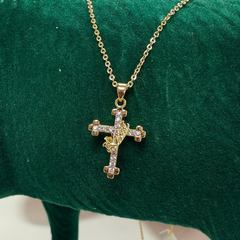 Gold cross necklace on a green surface with a blurred background