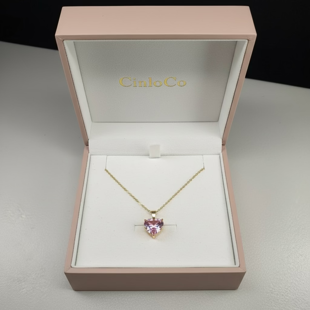 Gold necklace with a pink heart-shaped pendant on a white mannequin bust.