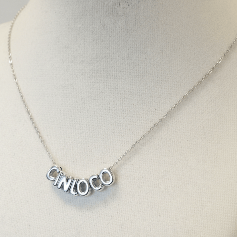 Silver necklace with 'CINLOCO' pendant on a mannequin bust.
