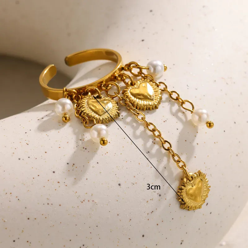 Gold bracelet with heart-shaped charms and pearls on a textured surface