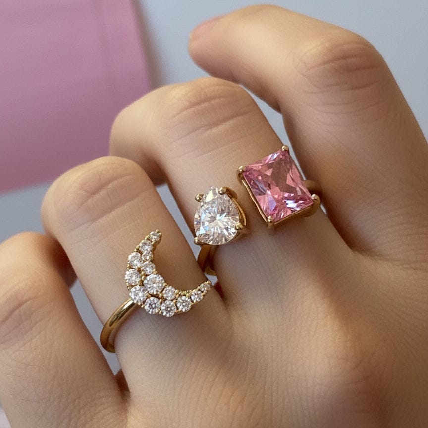 Close-up of a hand wearing two gold rings with pink and clear gemstones.