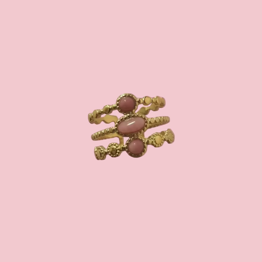 Gold ring with pink stones on a pink background